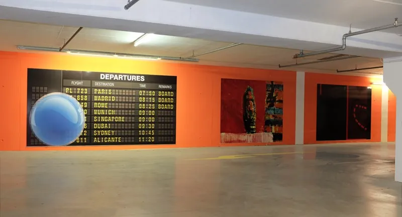 Tiefgarage mit orangefarbener Wand und Abflugtafel-Motiv
